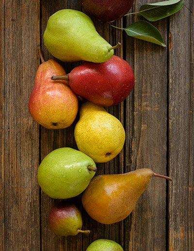 A medley of pear varieties on a wooden plank background